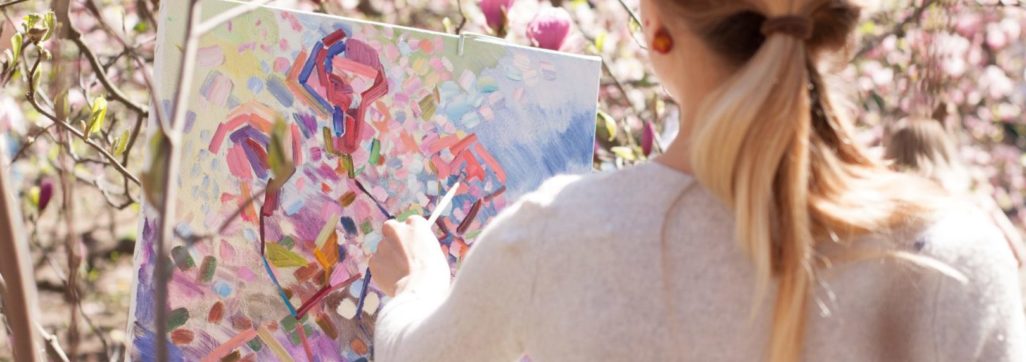 woman in white long sleeve shirt holding white and blue floral painting